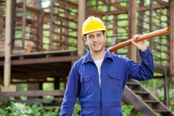 Lächelnder Arbeiter mit Rohr auf der Baustelle — Stockfoto