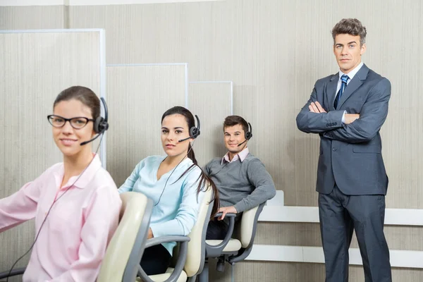 Selbstbewusster Geschäftsmann steht Team im Call Center zur Seite — Stockfoto
