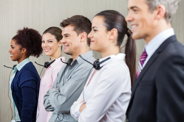 Representante sorridente do serviço ao cliente em pé com colegas — Fotografia de Stock