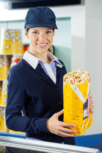 Hermoso trabajador sosteniendo palomitas de maíz en el contador de concesión de cine —  Fotos de Stock