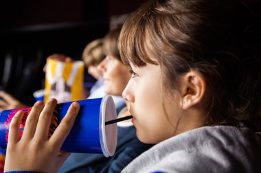 Girl Drinking Cola While Watching Movie In Theater clipart