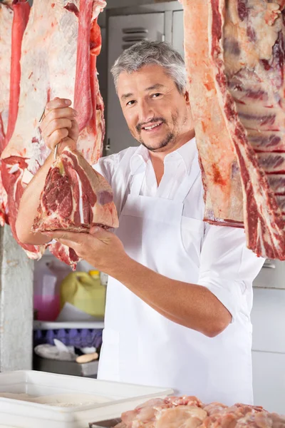 Selbstbewusster Metzger mit rohem Fleisch — Stockfoto