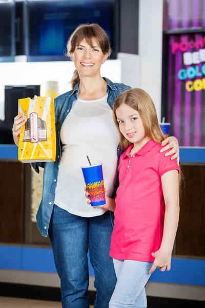 Мать и дочь держат попкорн и пьют в кино — стоковое фото