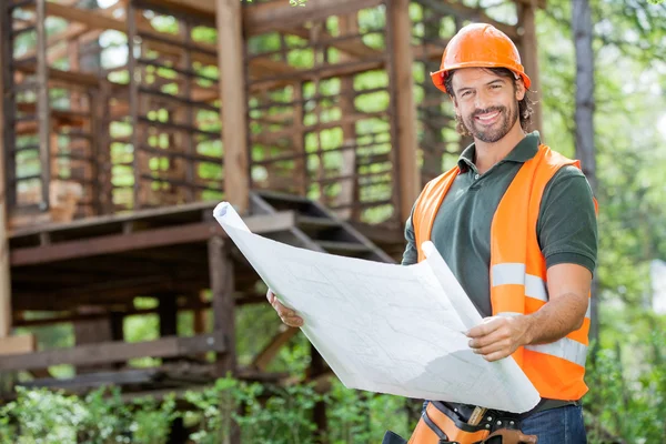 Glücklicher männlicher Architekt hält Blaupause vor Ort — Stockfoto