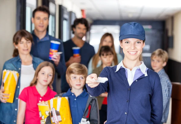 Trabajador feliz sosteniendo entradas mientras las familias en segundo plano en Cin —  Fotos de Stock