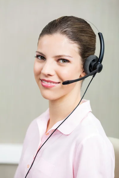 Dipendente del call center femminile sorridente che utilizza le cuffie — Foto Stock