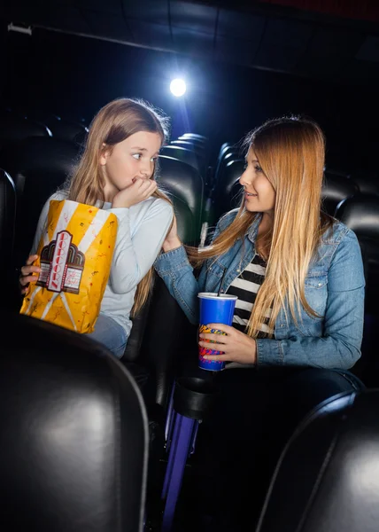 Мать утешает испуганную дочь в кинотеатре — стоковое фото