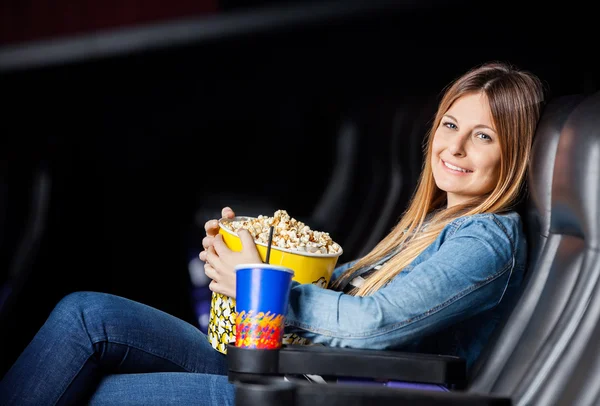 Улыбающаяся женщина с закусками в кинотеатре — стоковое фото