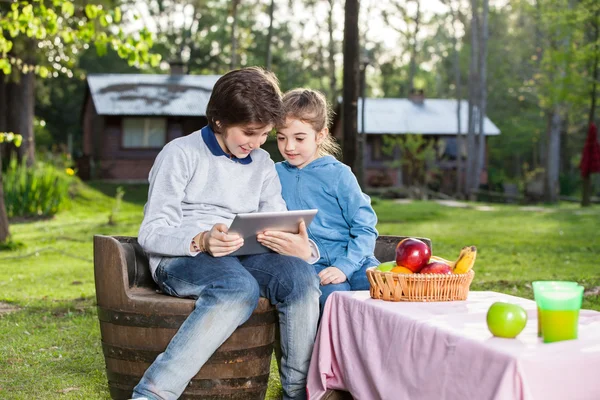 Lächelnde Geschwister mit Tablet-Computer auf Campingplatz — Stockfoto