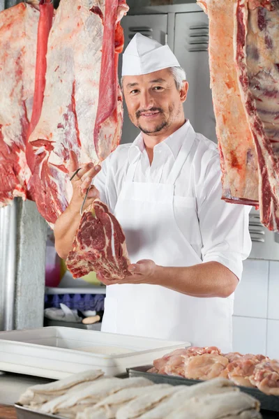 Carnicero de confianza sosteniendo carne cruda — Foto de Stock