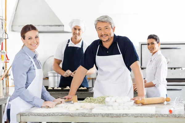 Vertrouwen mannelijke en vrouwelijke chef-koks bereiden Pasta in Kitchen — Stockfoto