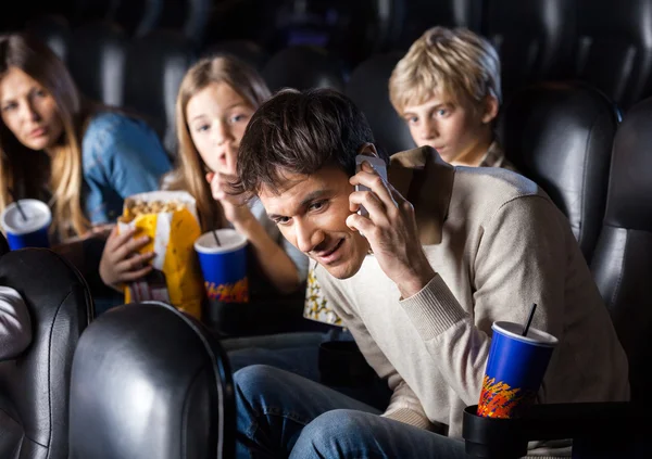 Famille regardant l'homme en utilisant le téléphone mobile dans le théâtre — Photo