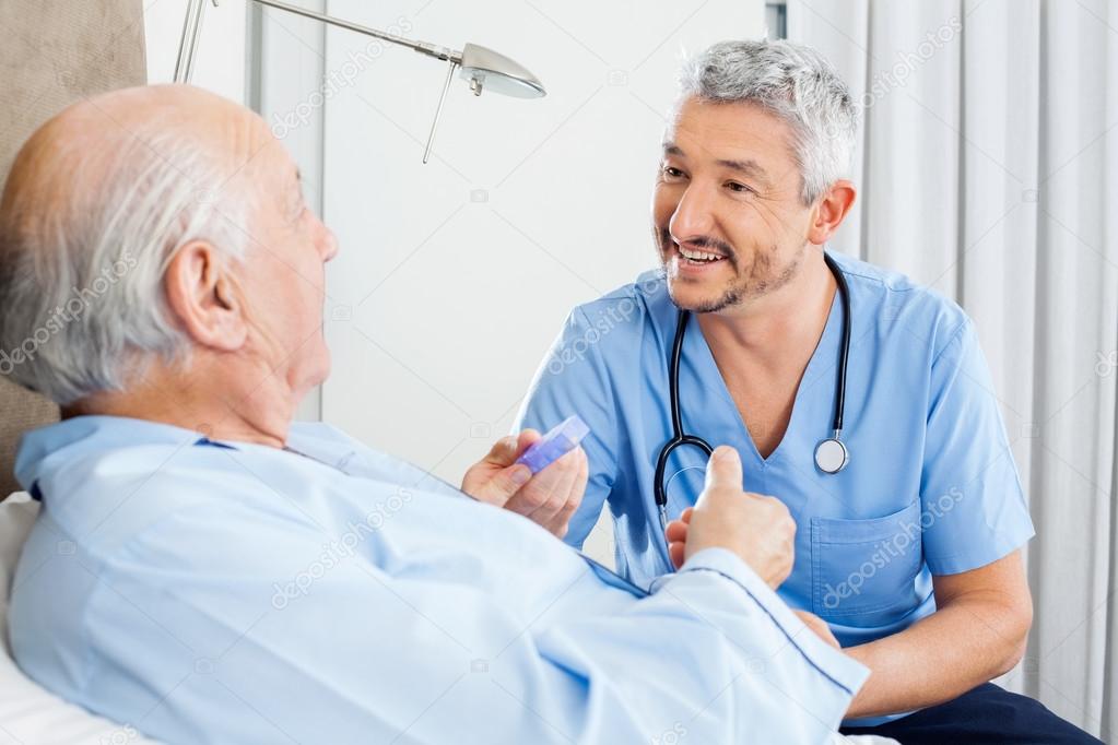 Happy Caretaker Discussing Prescription With Senior Man