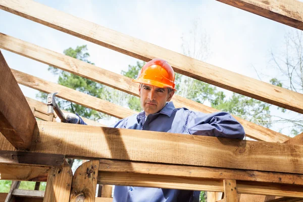 Selbstbewusster Bauarbeiter hämmert Nagel auf Holzrahmen — Stockfoto