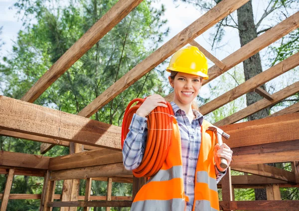 Trabalhadora da construção feminina segurando tubulação e martelo no local — Fotografia de Stock