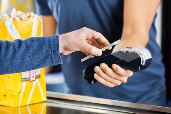 Homem fazendo pagamento através da tecnologia NFC no cinema — Fotografia de Stock