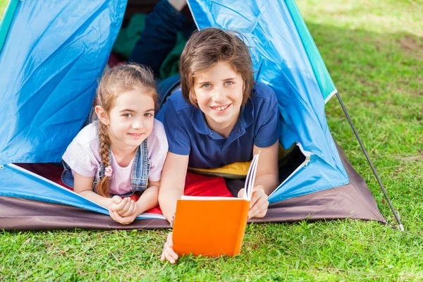 Irmãos leitura livro na tenda — Fotografia de Stock