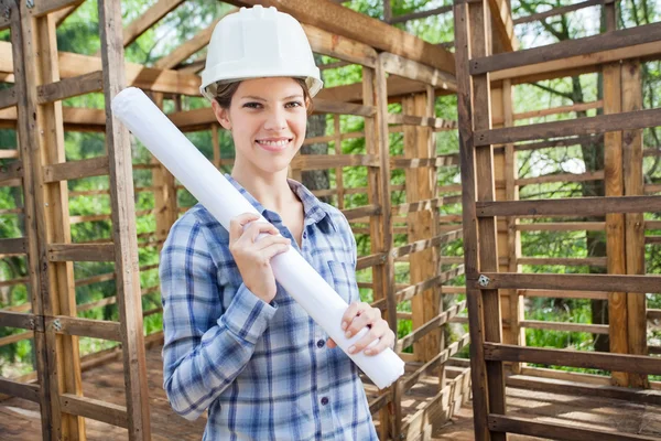 Leende ingenjör Holding Blueprint i trä stuga — Stockfoto