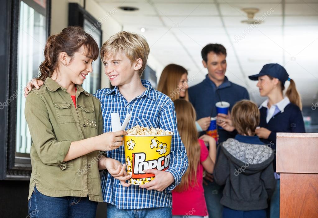 Brother And Sister Holding Popcorn At Cinema