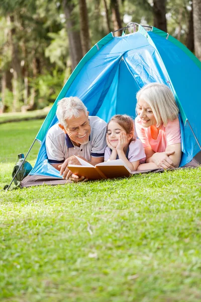 Großeltern lesen Buch für Enkelin auf Campingplatz — Stockfoto