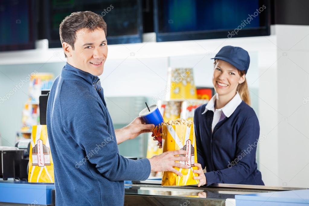 Man Buying Popcorn And Drink From Seller At Concession Stand