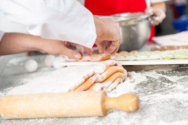 Midsection Of Chefs Preparing Ravioli Pasta At Counter