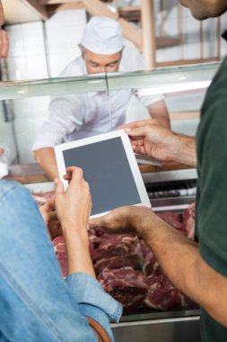 Couple Using Digital Tablet At Butchery