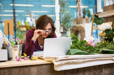 Çiçekçide Laptop kullanırken gözlük tutan çiçekçi