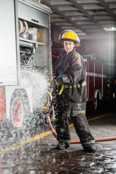 Bombera segura rociando agua durante la práctica — Foto de Stock