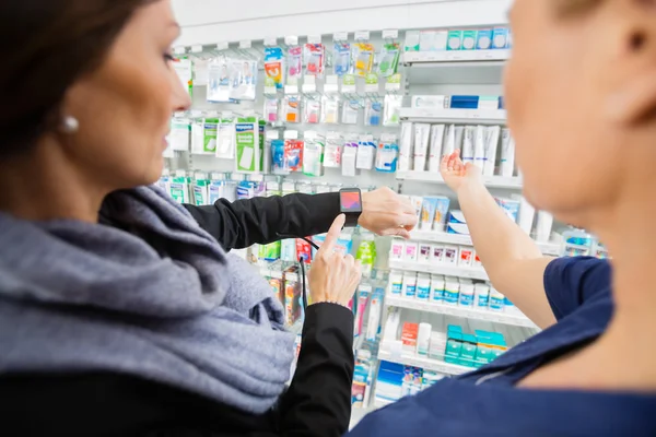 Cliente femenino mostrando Smartwatch a farmacéutico en farmacia —  Fotos de Stock