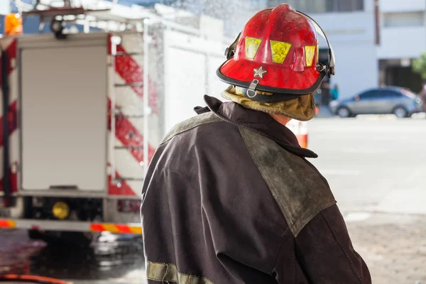 Feuerwehrmann versprüht Wasser an Feuerwache — Stockfoto