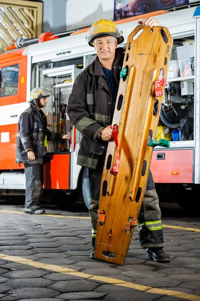 Portret van vertrouwen brandweerman houden houten brancard — Stockfoto