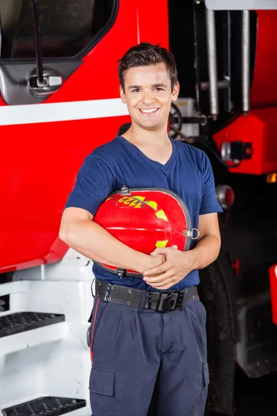Casque de pompier heureux tenant à la caserne de pompiers — Photo