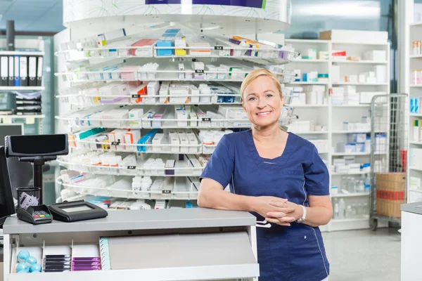 Farmacêutico confiante apoiando-se no contador de dinheiro na farmácia — Fotografia de Stock