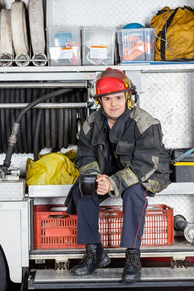 Selbstbewusster Feuerwehrmann hält Kaffeebecher in Lastwagen — Stockfoto