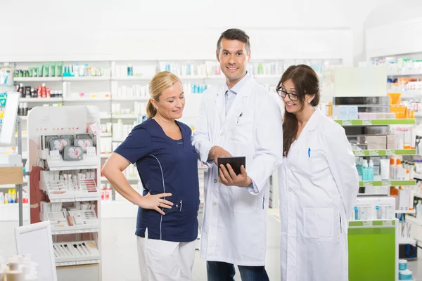 Farmacêutico confiante usando comprimido digital com colegas de trabalho — Fotografia de Stock