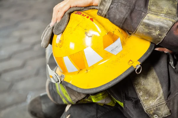 Bombero sosteniendo casco amarillo en estación de bomberos — Foto de Stock