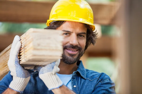 Usměvavý dělník nesoucí svázané Dřevěná prkna — Stock fotografie