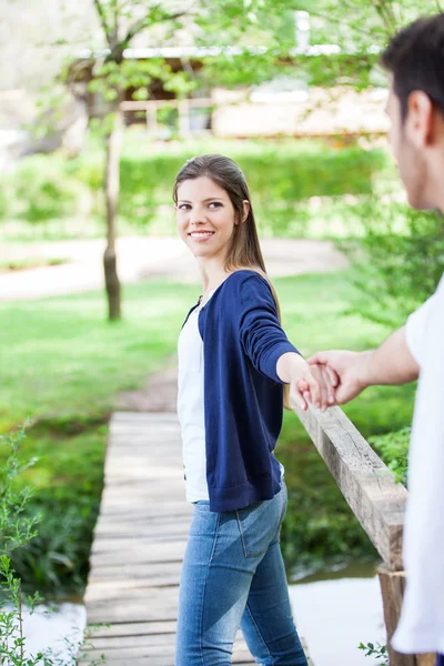 Молодая женщина держит за руку бойфренда в парке — стоковое фото
