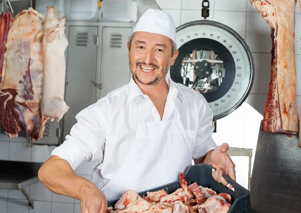 Metzger trägt Fleischstücke in Kiste in Metzgerei — Stockfoto