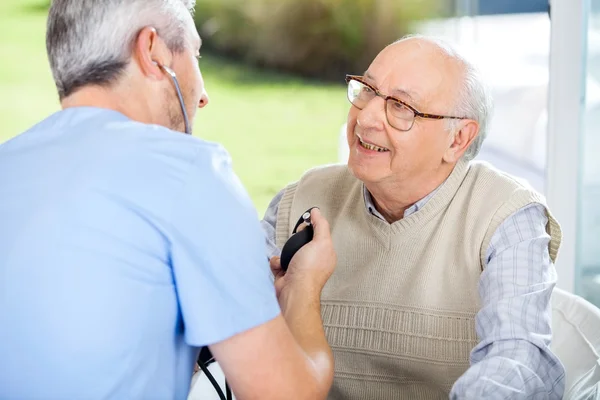 Medico maschile che misura la pressione sanguigna dell'uomo anziano — Foto Stock