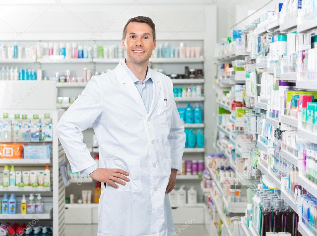 Male Pharmacist Standing With Hands On Hip In Pharmacy
