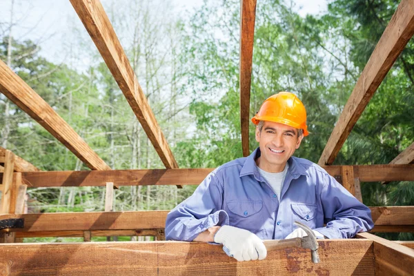 Šťastný stavební dělník drží kladivo na místě — Stock fotografie