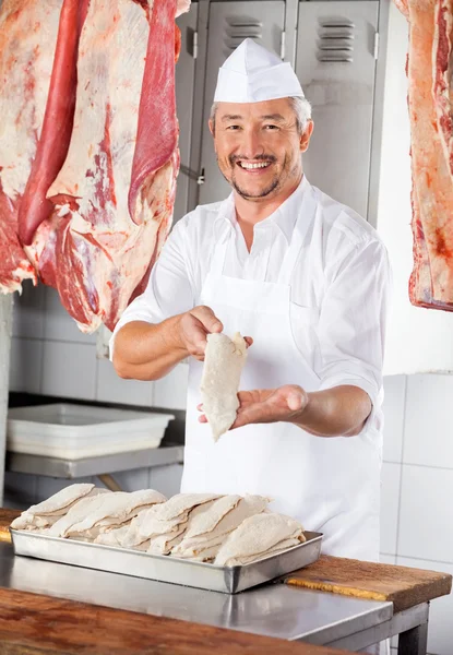 Carniceiro mostrando pedaços de frango cobertos com farinha — Fotografia de Stock