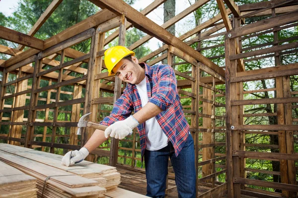 Trabalhador de construção confiante martelando prego na prancha de madeira — Fotografia de Stock