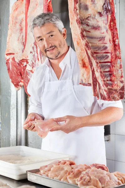Мясник держит куриное мясо на прилавке — стоковое фото