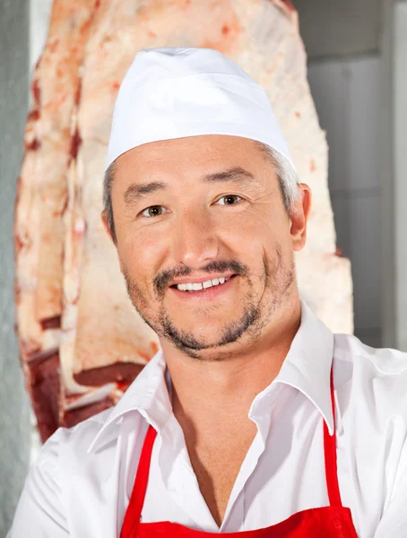Carnicero confiado sonriendo en la carnicería — Foto de Stock