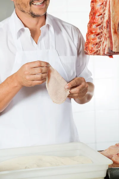 Açougueiro segurando carne coberta com farinha — Fotografia de Stock