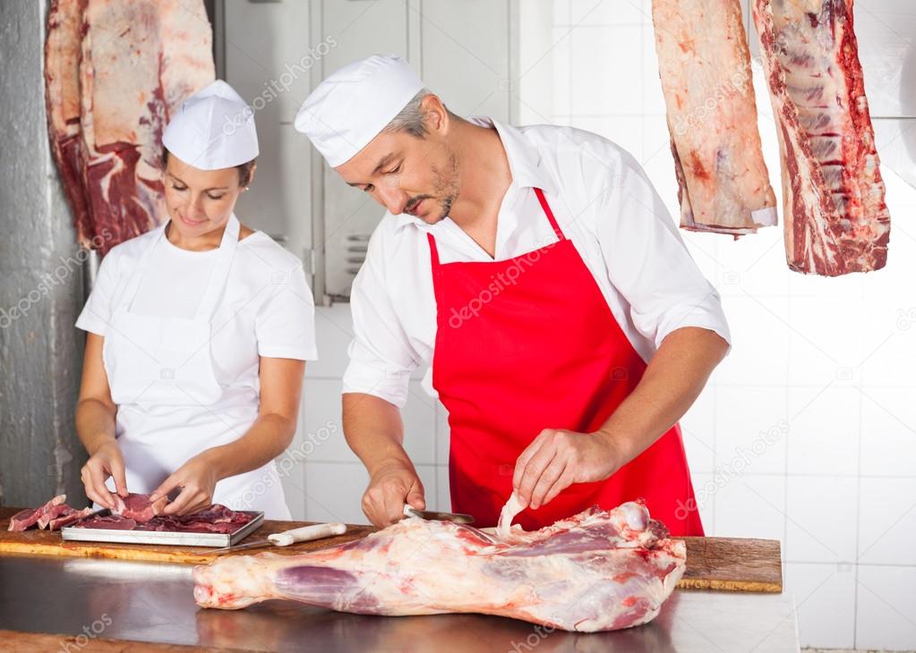 Butchers Working At Counter In Shop