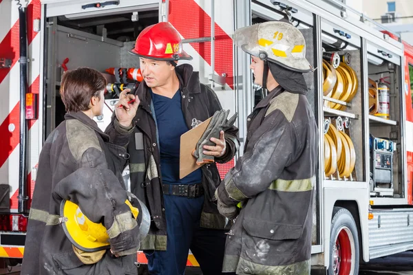 Пожежник обговорює з колегами проти вантажівки — стокове фото